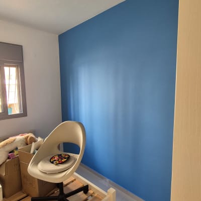 קיר צבוע בכחול בחדר עם כיסא ומיטה