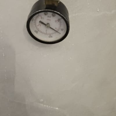 מד לחץ מים מחובר לצינור על קיר רטוב