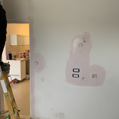 אדם צובע קיר עם שפכטל, סולם, תיקוני טיח