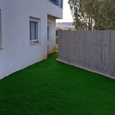 דשא סינתטי ירוק ליד גדר במרפסת
