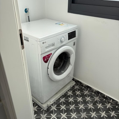 מכונת כביסה בחדר עם רצפת אריחים מעוצבת