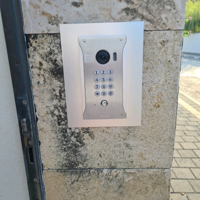 אינטרקום עם מצלמה ולוח מקשים על קיר אבן