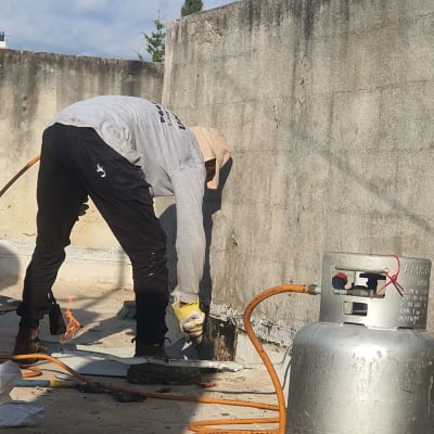 אדם עובד עם מבער גז לאיטום קיר בטון