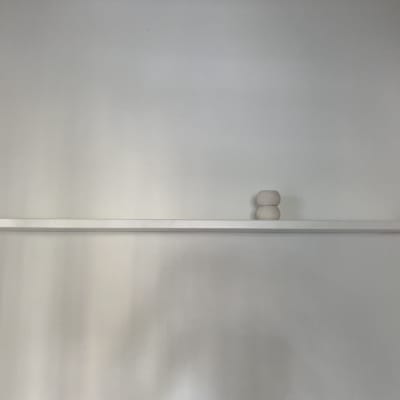 מדף עץ לבן עם שני חפצים מעץ