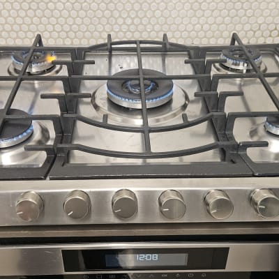 כיריים גז עם להבות כחולות וכלי עבודה על השיש