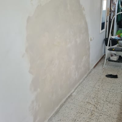 קיר עם טיח מתוקן ליד חלון עם תריסים