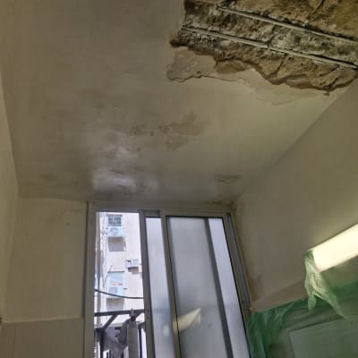 תקרה עם נזקי רטיבות וקיר מתקלף ליד חלון