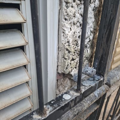 קיר עם סדקים ליד חלון ותריסים