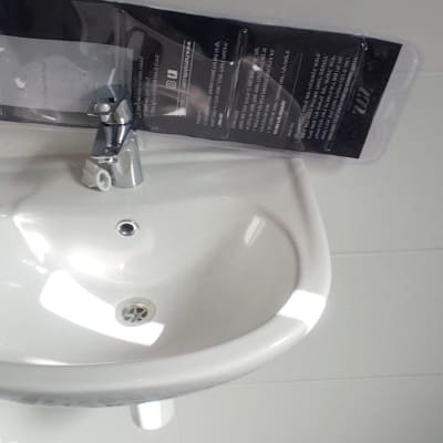 כיור לבן עם ברז על רקע אריחים מעוצבים