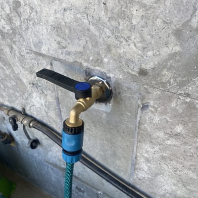 ברז מים עם צינור מחובר לקיר אבן