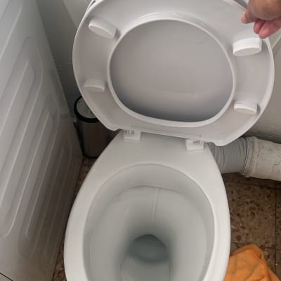 אסלה פתוחה עם מכסה לבן וחלקי צנרת