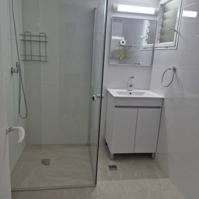 חדר אמבטיה עם מקלחון וכיור לבן