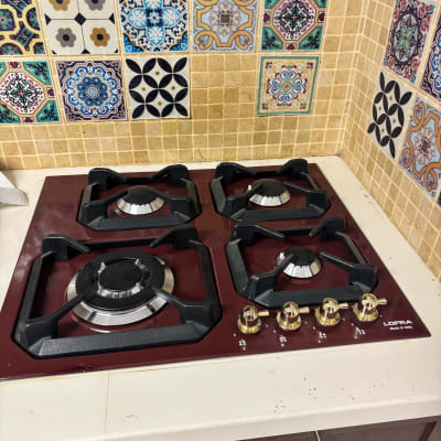 כיריים גז עם כפתורים מוזהבים על רקע אריחים מעוצבים