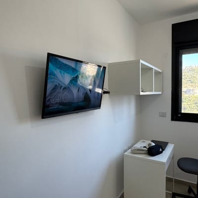 טלוויזיה מותקנת על קיר ליד שולחן קטן וכיסא