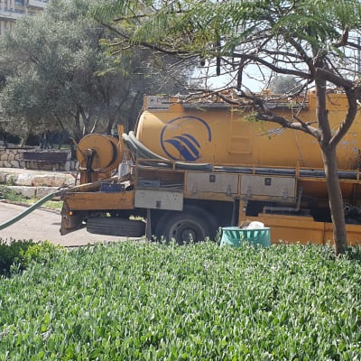 משאית ואקום צהובה עם צינור ירוק מחובר