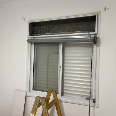 תריסים מותקנים על חלון עם סולם ליד