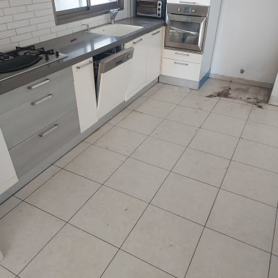 מטבח עם רצפה מלוכלכת וכתמים ליד התנור