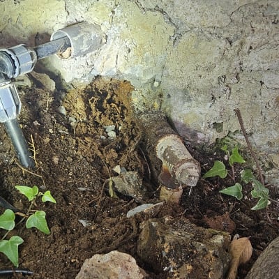 צינור מים ישן עם חלודה ודליפה בקיר בטון