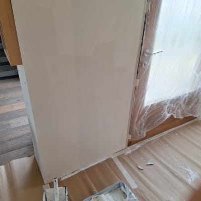 ציוד צביעה כולל רולר ומגש צבע ליד קיר צבוע חלקית