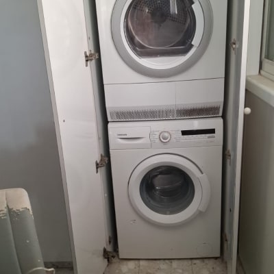 מכונת כביסה ומייבש בארון פתוח עם כלים חד פעמיים