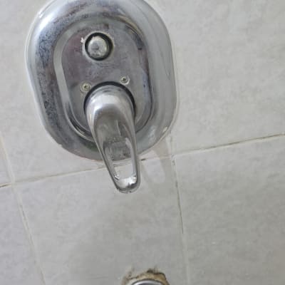 ברז מים עם ידית מתכת על קיר אריחים