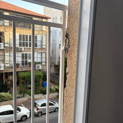 מעקה מתכת ליד חלון עם נוף לבניינים ורחוב