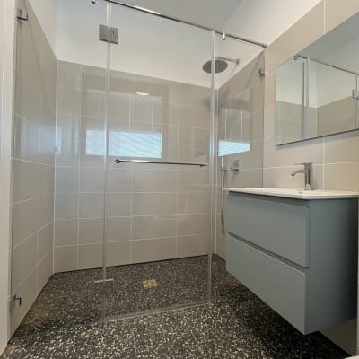 מקלחון זכוכית בחדר אמבטיה מודרני עם אריחים אפורים