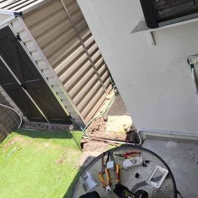 כלים וחלקים חשמליים על שולחן זכוכית בחוץ ליד שקע חשמל בקיר