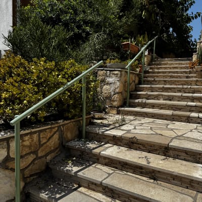 מדרגות אבן עם מעקה מתכת וצמחייה מסביב