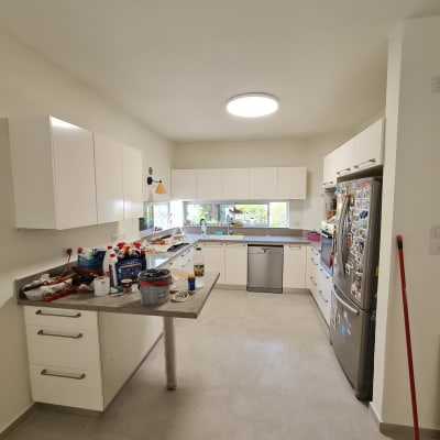 מטבח עם ארונות לבנים וכלי עבודה על השיש