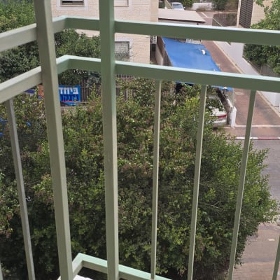 צביעת מעקה מתכת במרפסת בגוון ירוק בהיר עם כיסוי הגנה