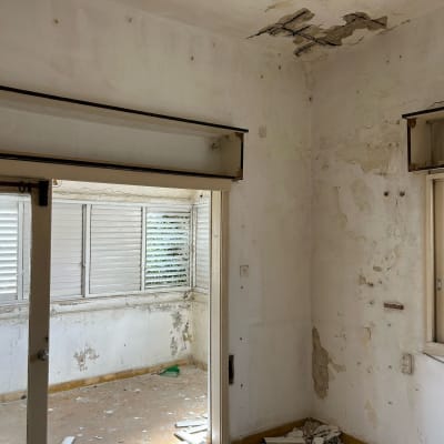 חדר עם קירות מתקלפים ותקרה מתפוררת, פסולת בנייה על הרצפה
