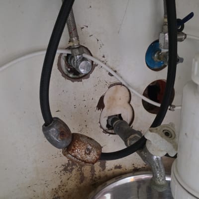 צנרת מתחת לכיור עם סימני חלודה ונזילה