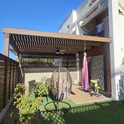 פרגולה מעץ עם כיסאות גינה ונדנדה בחצר