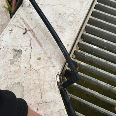 צינור דולף ליד רשת מתכת על רצפה סדוקה