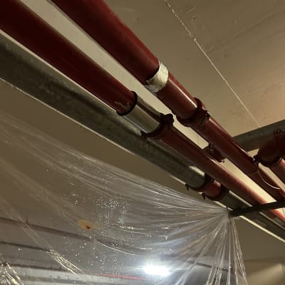 צינורות אדומים עם חיבורים מתכתיים בתקרה