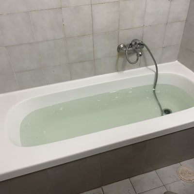 אמבטיה מלאה מים עם ברז ומקלחת יד