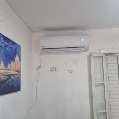 מזגן מותקן על קיר לבן עם שלט על הספה