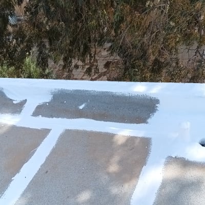 איטום גג עם חומר לבן על משטח בטון