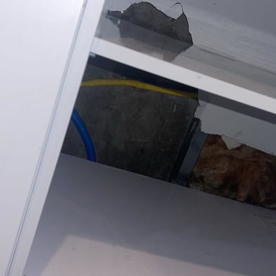 ארון פתוח עם חור בקיר וצינורות חשופים