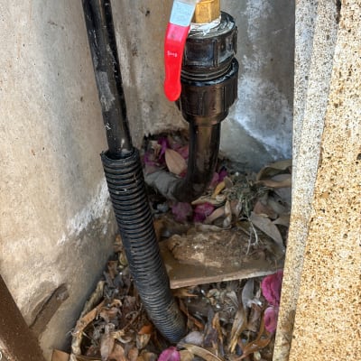 שסתום מים עם ידית אדומה וצינור שחור