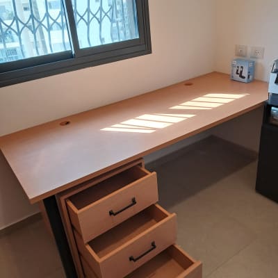 שולחן עץ עם מגירות פתוחות ליד חלון