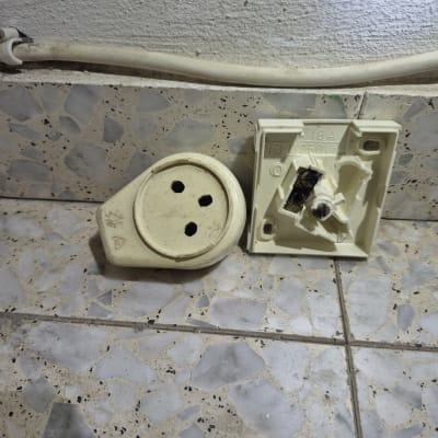 שקע חשמלי מפורק על רצפה מרוצפת