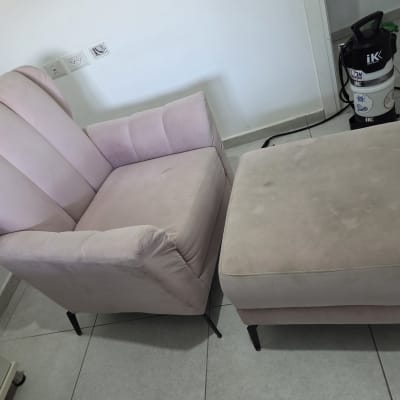 כורסה ורודה ומכשיר ניקוי על רצפה אפורה