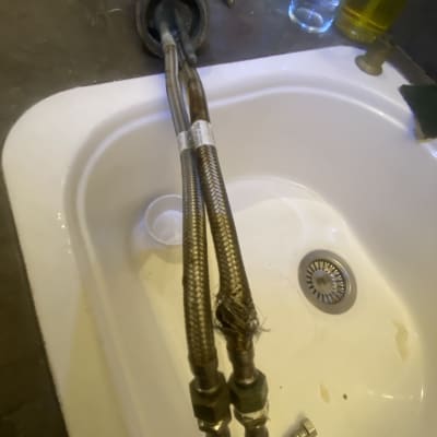 צינורות מתכת מחוברים לברז בכיור מטבח