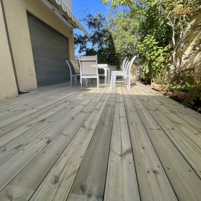 דק עץ עם שולחן וכיסאות בגינה