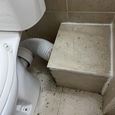 אסלה עם צינור פלסטיק גמיש מחובר לקיר