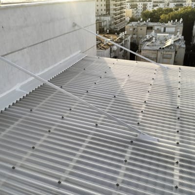 גג מתכת עם ברגים ותמיכה על קיר בטון