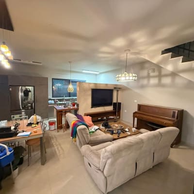 סלון עם ספה, טלוויזיה ופסנתר, מטבח ברקע