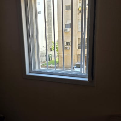 סורגים ישרים לבנים ממתכת המותקנים בחלון בית